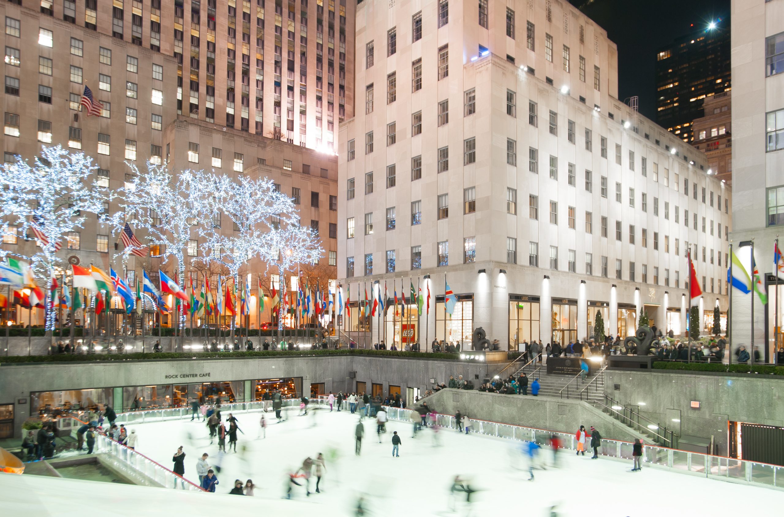 Rockefeller Center in New York City with an ice skating rink and people ice skating.